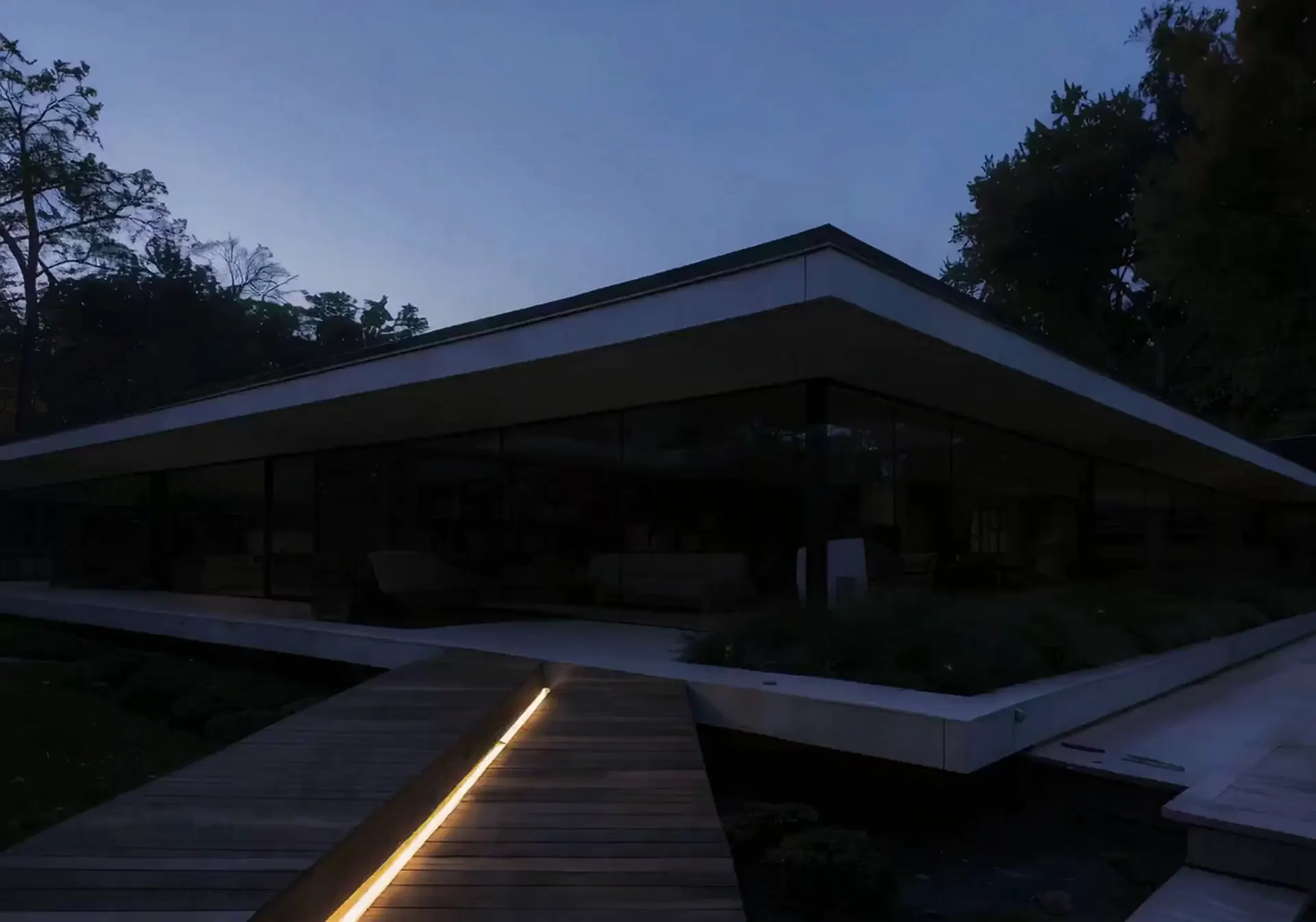 The same glass house at dusk with its interior lights off (illustrative, generated).